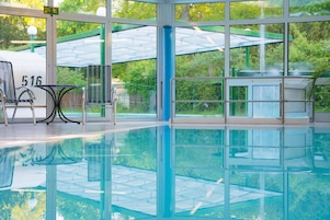Piscina interior transparente com vista para o verde lá fora.