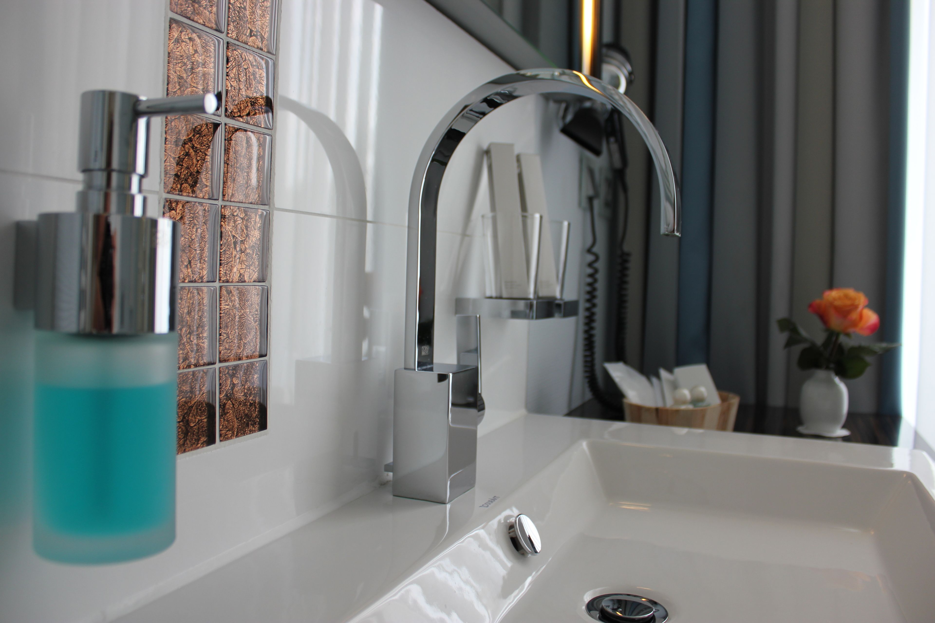 Une salle de bain moderne avec un robinet chromé, une douche en verre et un lavabo blanc.