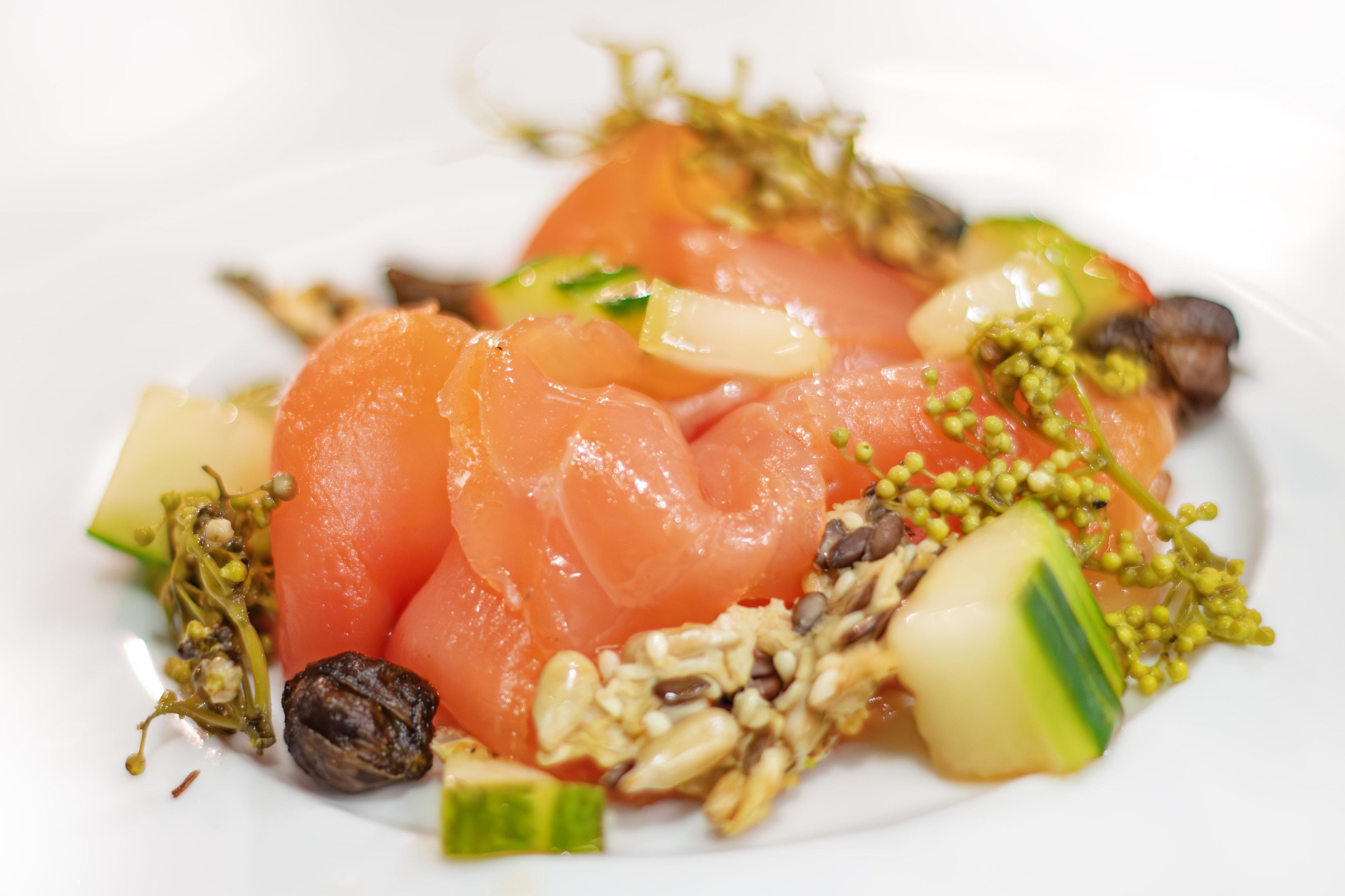 A plate of food with salmon, vegetables, and nuts.
