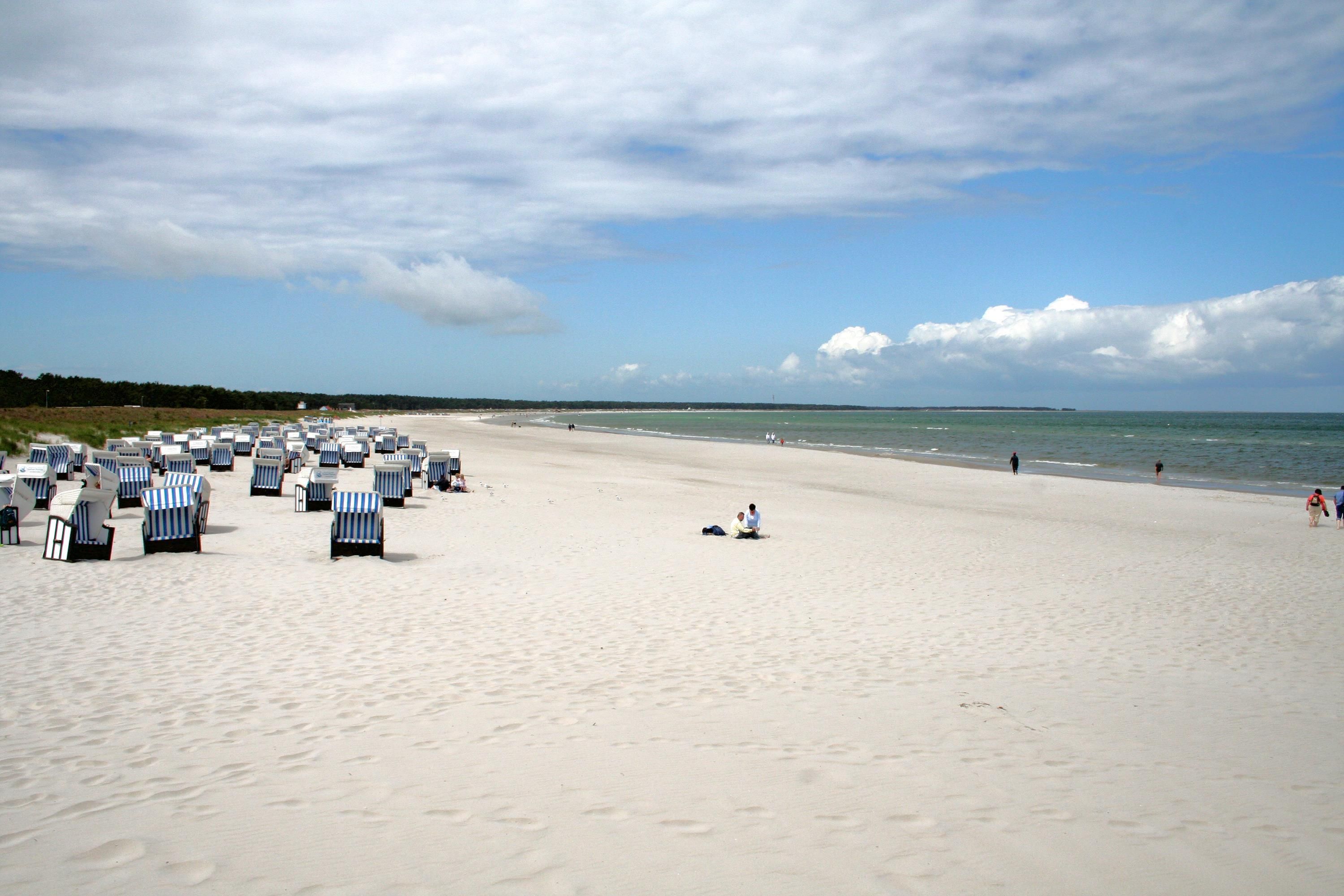 Ein Strand mit Reihen von gestreiften Liegestühlen und einem Sandufer.