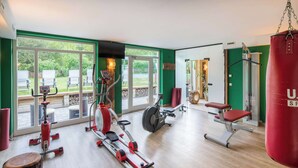 Une salle de sport équipée de machines de cardio, d’un sac de frappe et d’un banc de musculation.