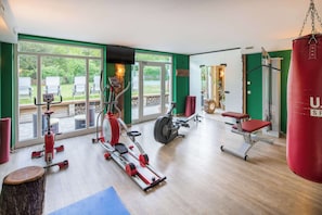 Een fitnessruimte met cardioapparaten, een bokszak en een bank.