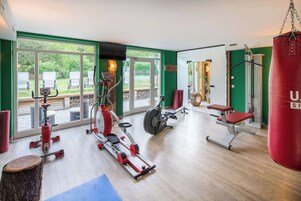 Un gimnasio con máquinas de cardio, un saco de boxeo y una banca.