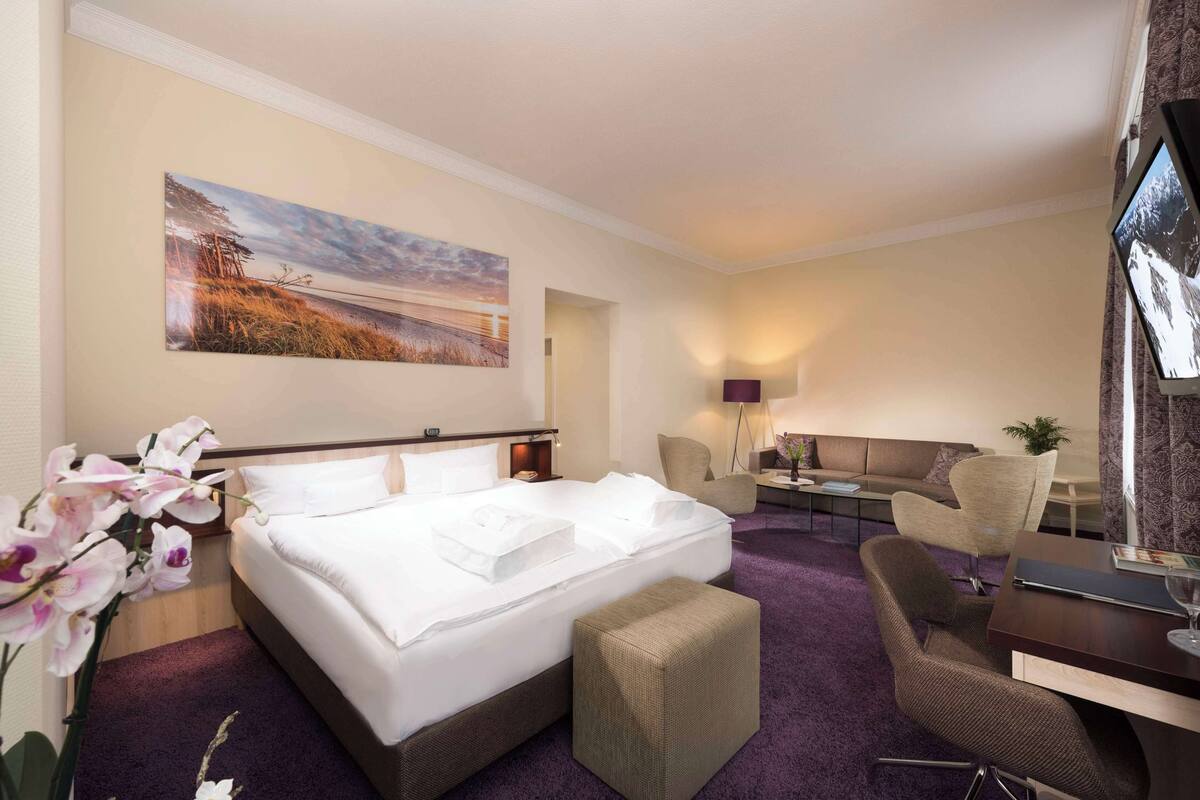 Een hotelkamer met een groot bed, een bank, een bureau en een televisie.