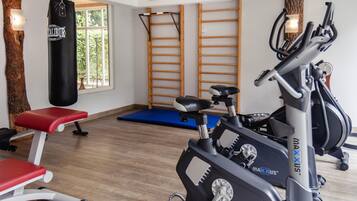 Ein Fitnessraum mit Trainingsgeräten, einem Sandsack und Holzboden.