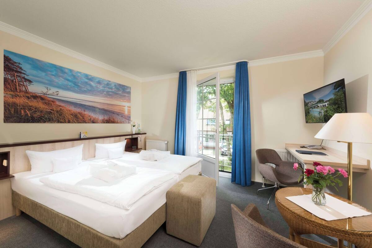 Een hotelkamer met een groot bed, een bureau, een stoel en uitzicht op de omgeving.