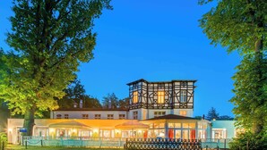 Un bâtiment européen de style traditionnel, doté d’une tour imposante, d’un espace extérieur abrité pour s’asseoir et d’un jardin bien entretenu.