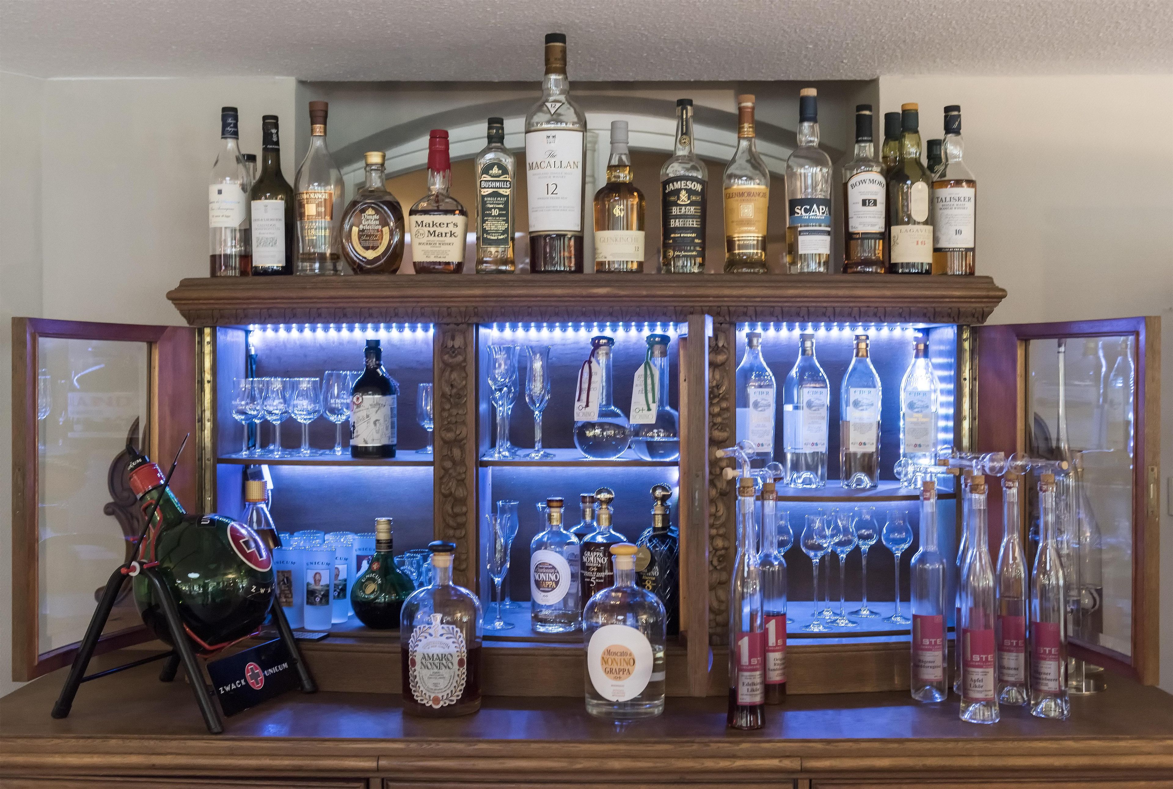 Zona de bar con diferentes botellas de licor y vasos.