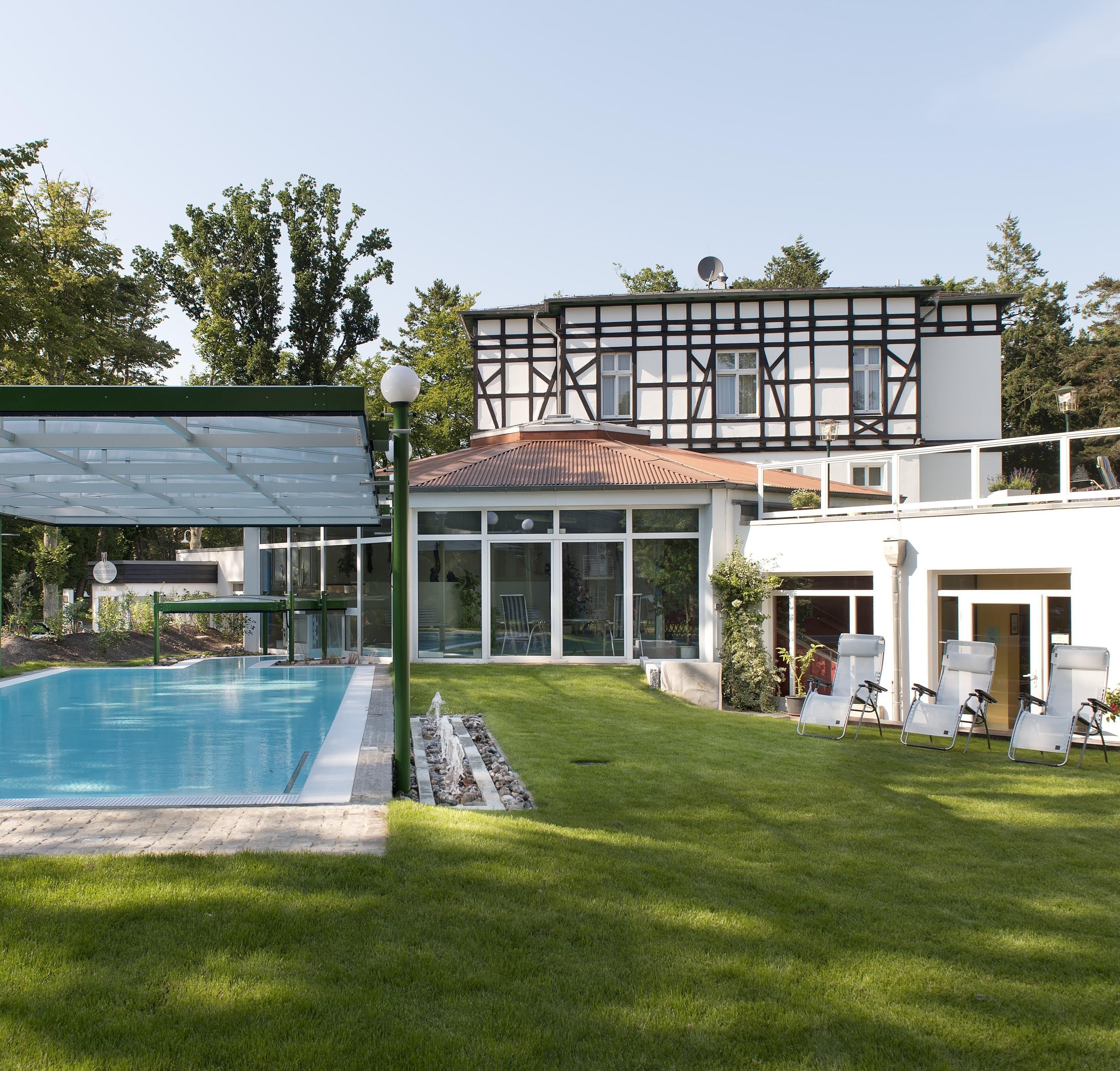 Une maison moderne dotée d’une piscine, d’un patio couvert et d’une pelouse bien entretenue.
