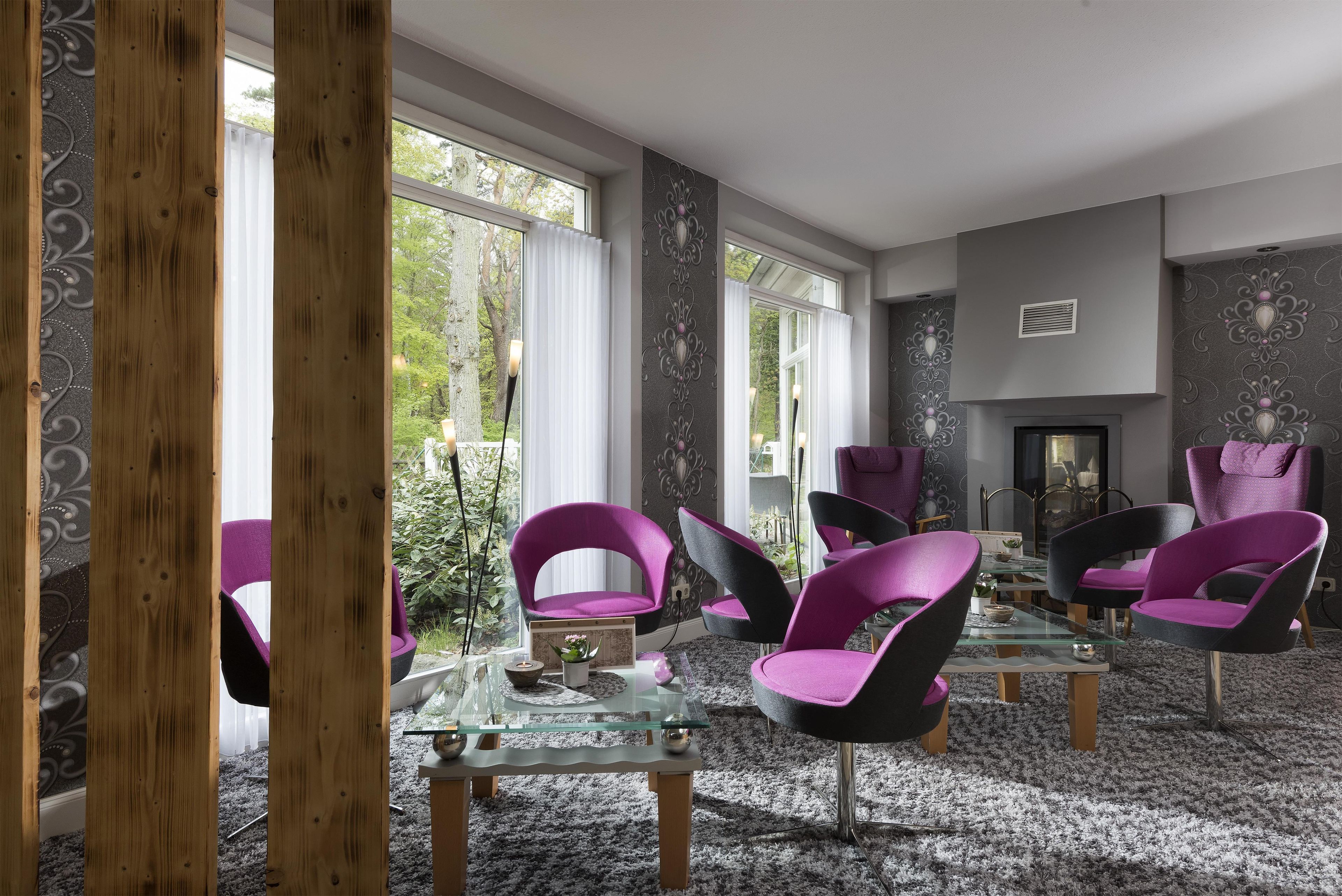 A modern living room with a fireplace, large windows, and purple chairs.