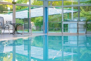 Una piscina techada, una piscina al aire libre, sombrillas