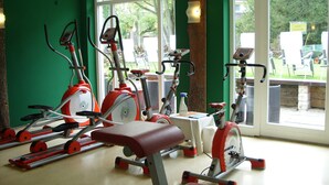 Une salle de sport équipée de vélos d’appartement et d’un banc, dotée de grandes fenêtres et d’un mur végétal.