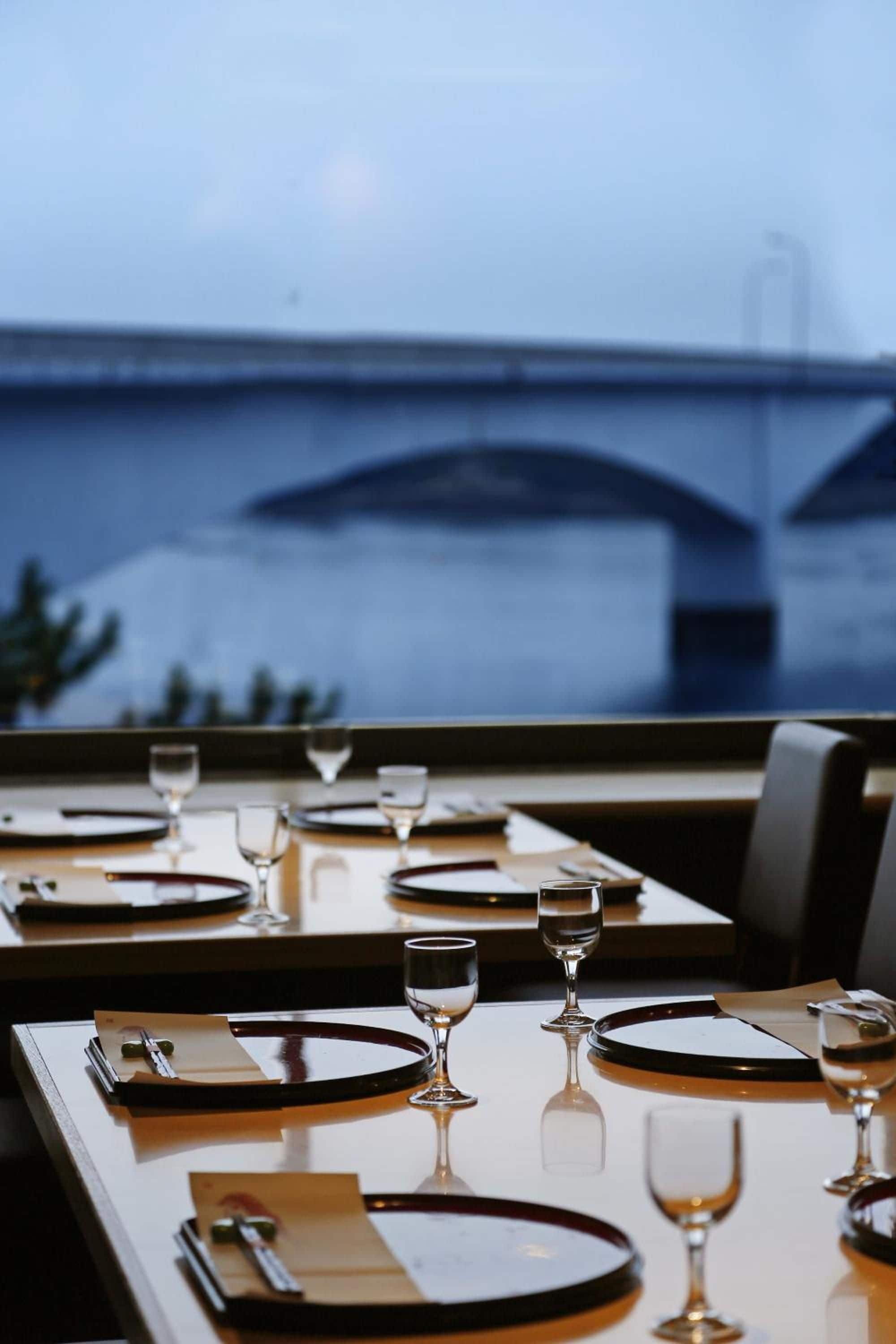 A table set for dining with a view of a bridge in the background.