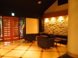 A lobby with a checkered floor, a stone wall, and a seating area with sofas and a coffee table. - Hotel Shosenkaku Romankan (Kamiamakusa)