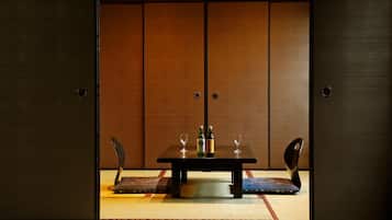 A traditional Japanese room with tatami flooring, a low table with two chairs, and a sliding door with a wooden finish.