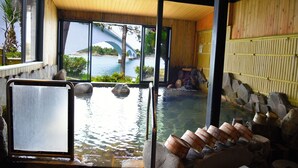 Perinteinen japanilainen onsen-kylpylä, jossa on puinen sisustus, näkymä sillalle ja kiviset kylpyaltaat.