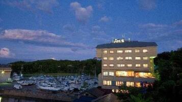 A hotel with multiple floors, a marina with boats, and a body of water in the foreground.
