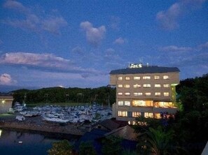 A hotel with multiple floors, a marina with boats, and a body of water in the foreground.