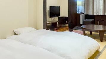 A hotel room with two beds, a television, a small table, and a view of the outdoors.