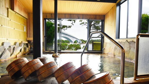 Perinteinen japanilainen onsen-kylpylä, jossa on puukylpyammeita ja kivinen kylpyallas.