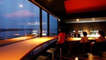 A bar area with a view of the cityscape through large windows.