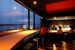 Eine Bar mit Blick auf die Stadt durch große Fenster.