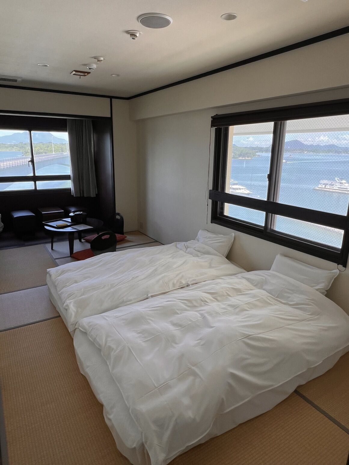 Ein Hotelzimmer mit Bett, Schreibtisch, Stuhl und einem Fenster mit Meerblick.