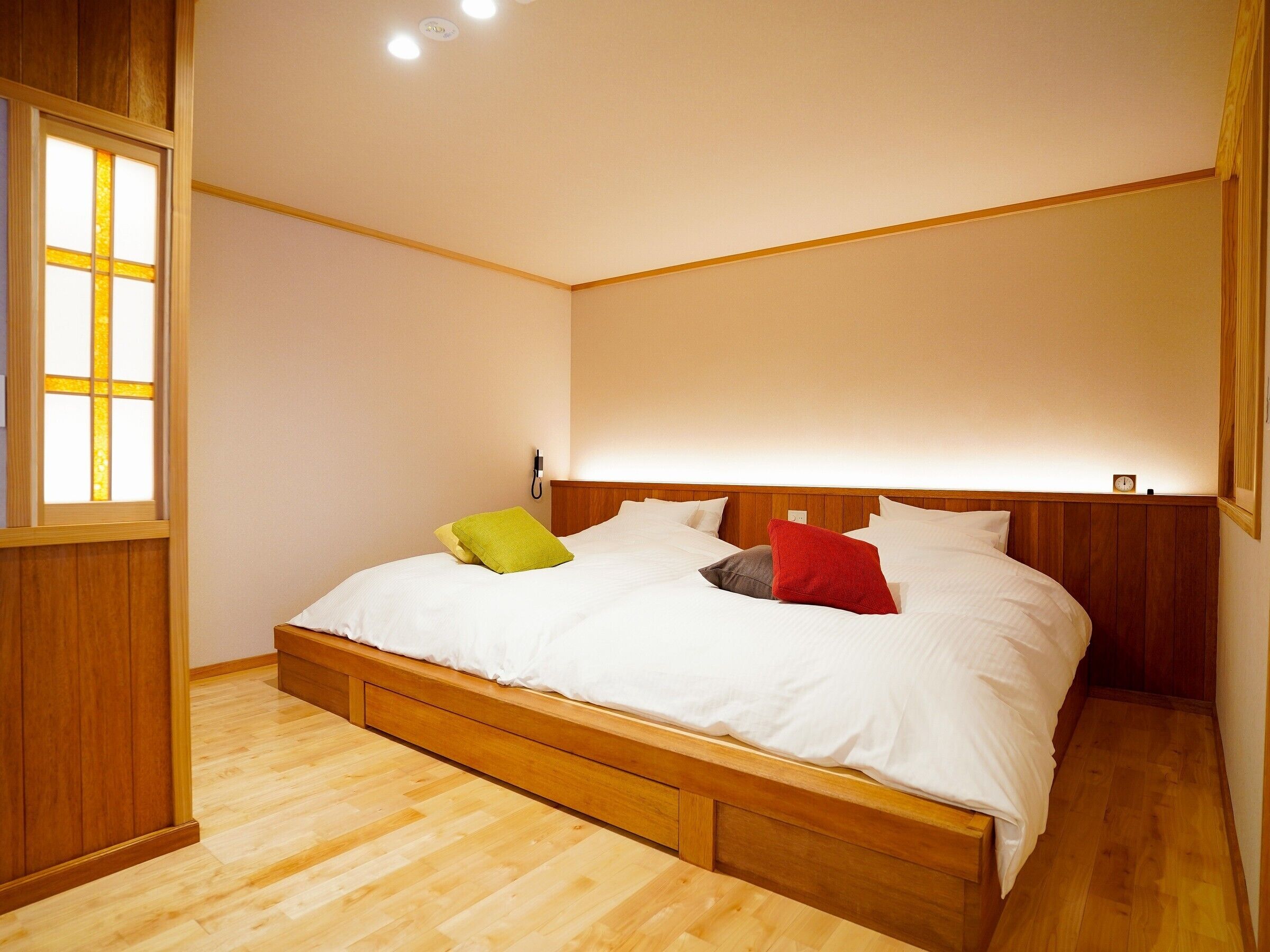 Ein Schlafzimmer mit Holzbettgestell, weißer Bettwäsche und Holzboden.