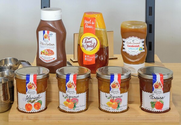 Various jars of preserves and condiments on a wooden shelf.