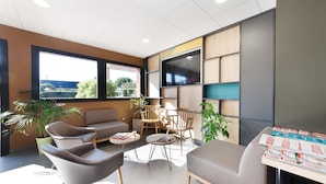 A modern lounge area with seating, a coffee table, and a flat-screen TV. - B&B Hôtel Albi (Albi)