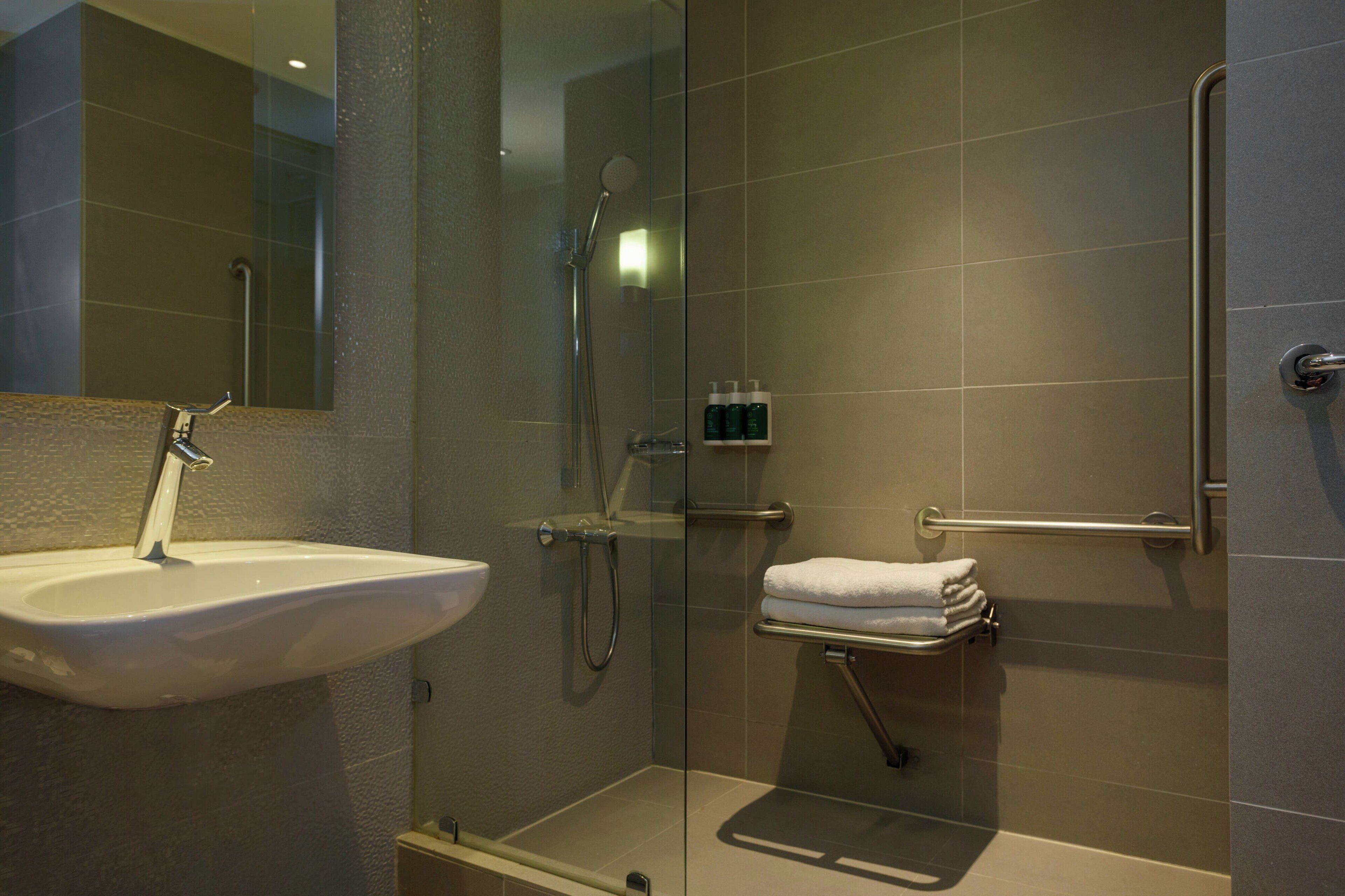 Un baño moderno con cabina de ducha de vidrio, lavamanos y un perchero para toallas.