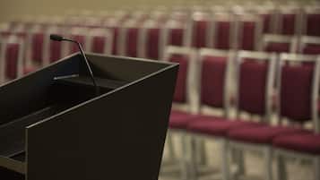 Un salón de conferencias con un atril y filas de sillas.