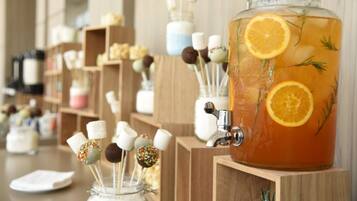 Um distribuidor de bebidas com um jarro de vidro cheio de líquido, decorado com rodelas de laranja e ervas.