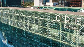 Un edificio moderno con facciata in vetro riflettente e la scritta "ODIE Kennedy" ben visibile.