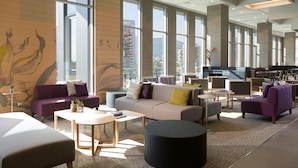 Eine geräumige Lobby mit moderner Möblierung, großen Fenstern und Blick auf die Stadt.