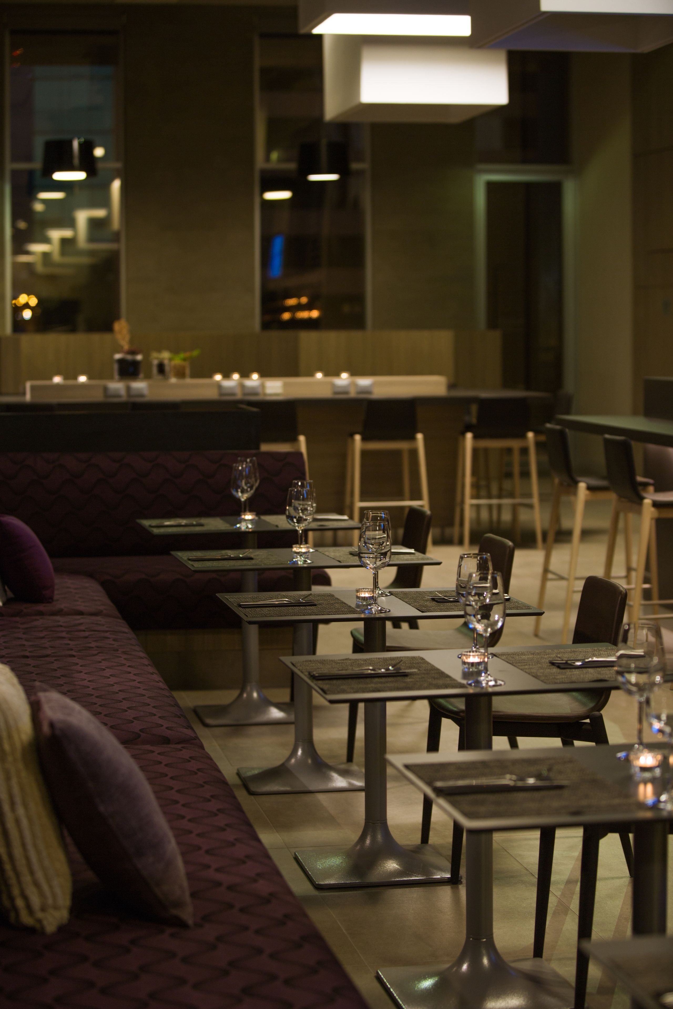A restaurant with tables and chairs, a bar area, and a seating area with cushions.
