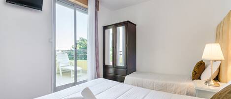 Una camera d'albergo con due letti, una televisione, un armadio e un balcone con una sedia.