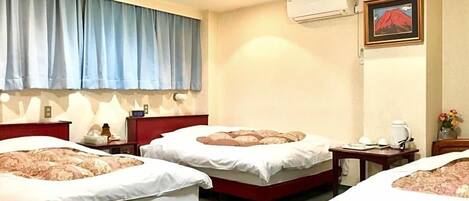 A hotel room with three beds, a large window with curtains, an air conditioning unit, and a framed picture on the wall.