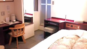 Ein Hotelzimmer mit einem Bett, einem Schreibtisch, einem Sessel, einem kleinen Tisch und einem Fenster.