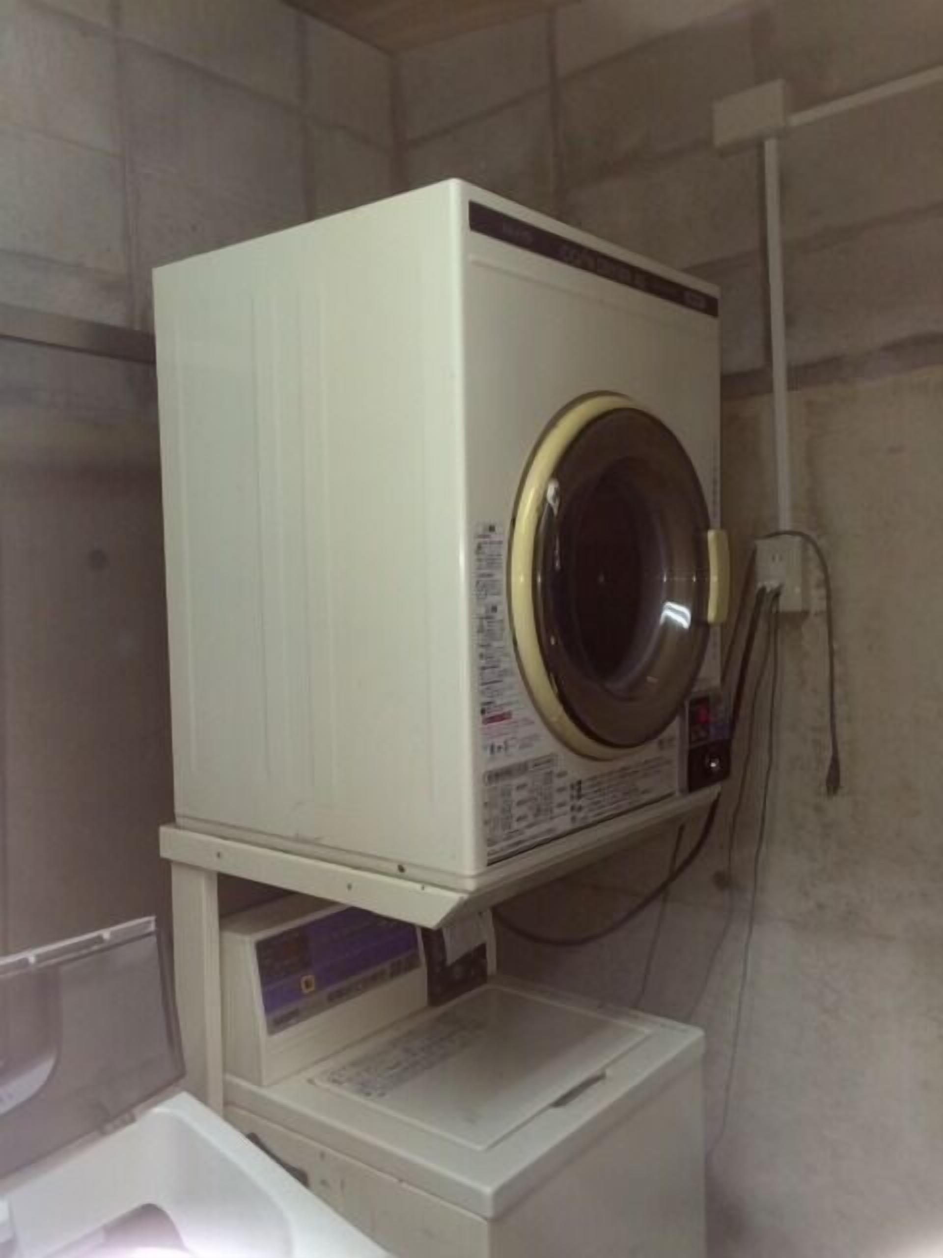 A compact, white, wall-mounted washer and dryer unit in a utility room.