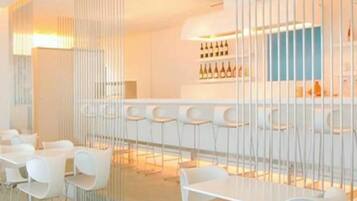 Zona de bar moderna con taburetes blancos y una vitrina de vinos.