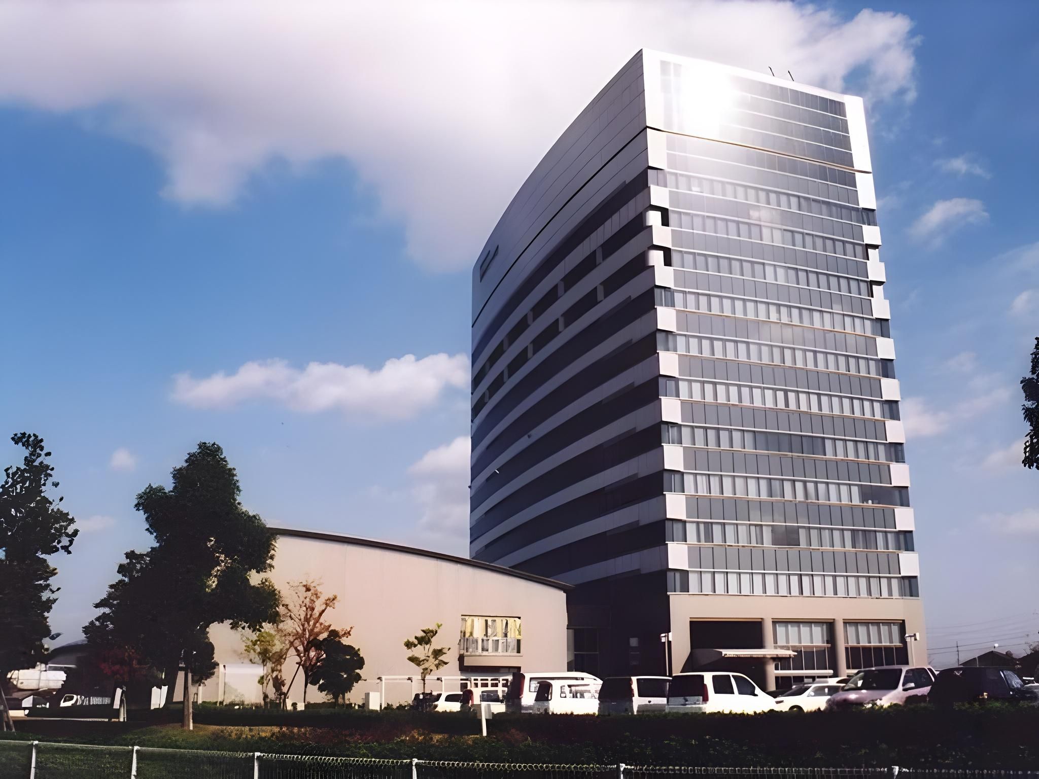 A modern building with a glass facade and a parking garage below.