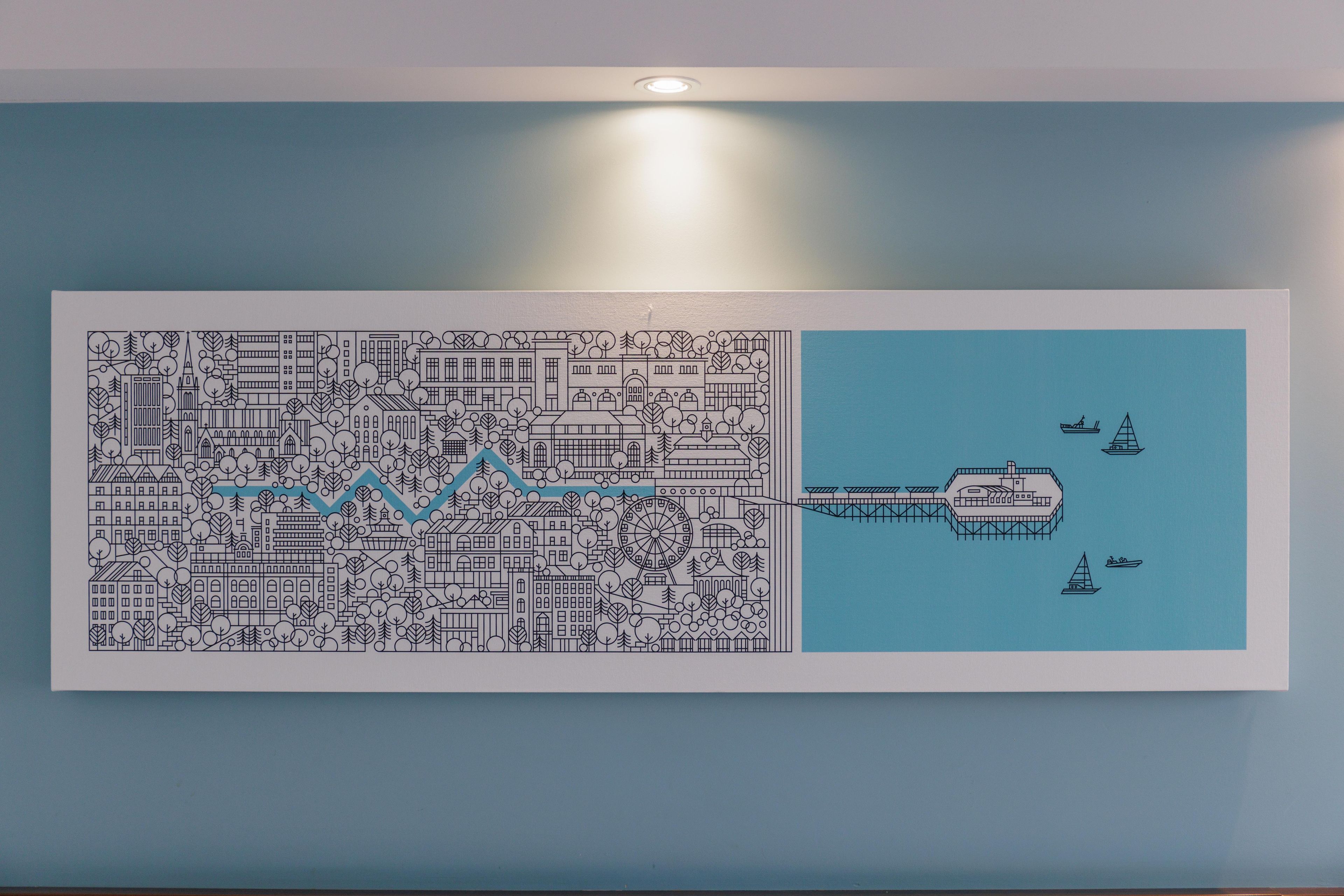 Una obra de arte enmarcada que muestra un paisaje urbano con un puente que conduce a un puerto con barcos.