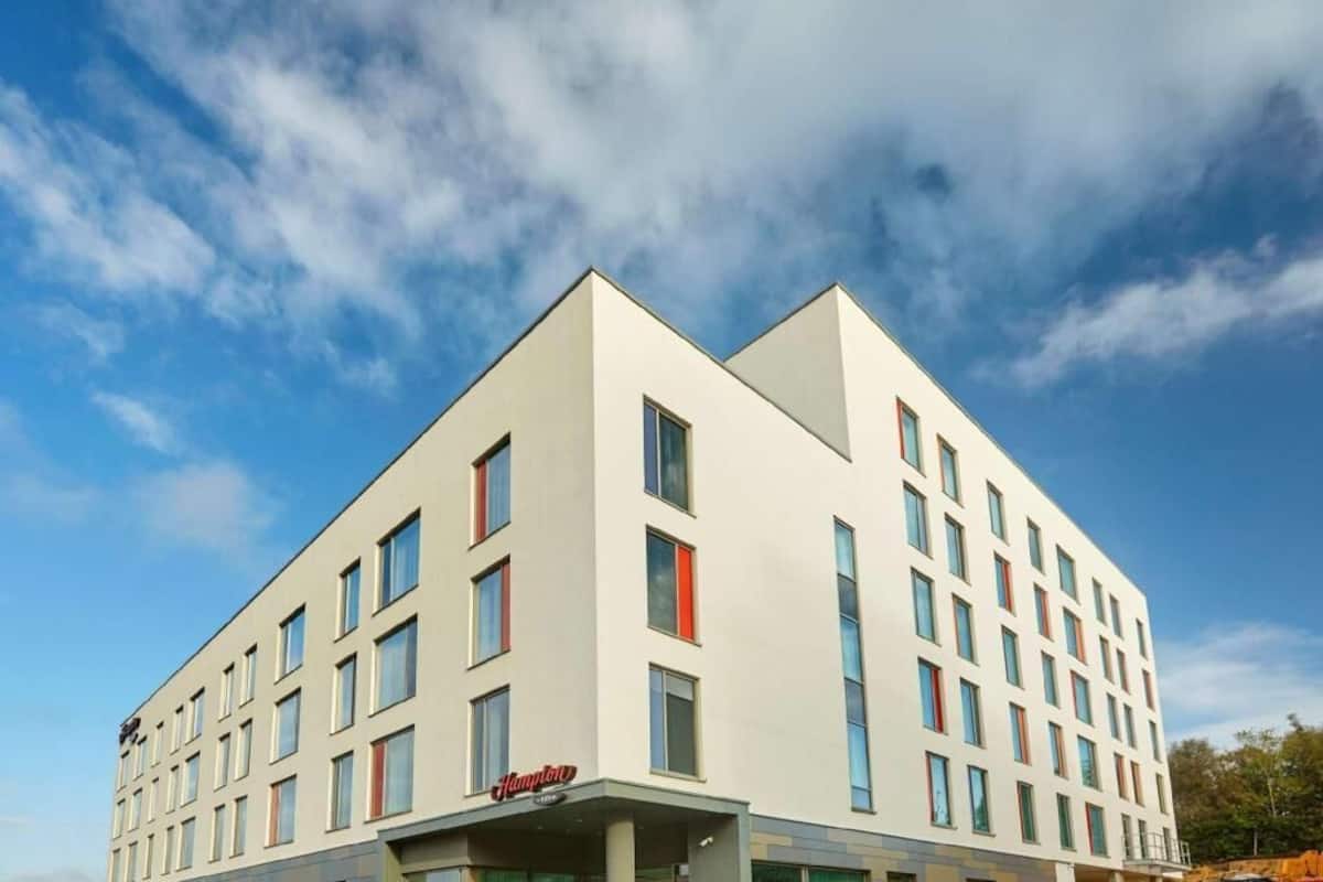 A modern hotel building with a flat roof, multiple windows, and a visible entrance.
