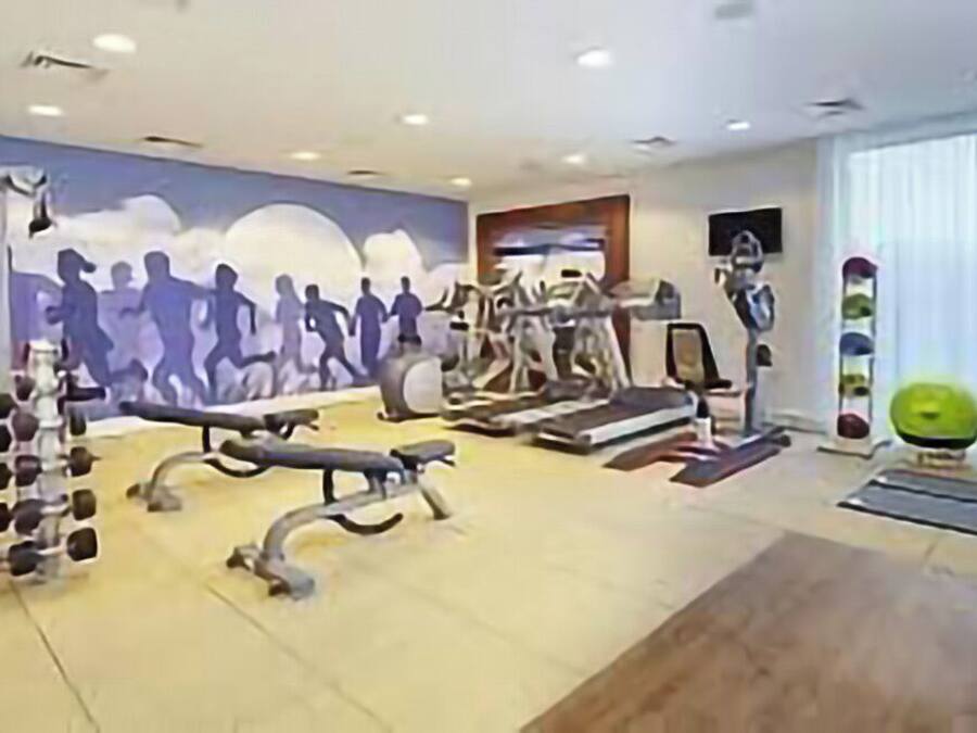 Ein Fitnessstudio mit Laufbändern, Gewichten und Trainingsbällen.