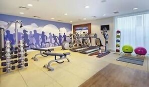 Un gimnasio con cintas de correr, pesas y pelotas de ejercicio.