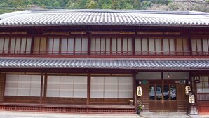 A traditional Japanese building with a tiled roof, wooden structure, and large windows. - Kamigoten Ryokan (Tanabe)