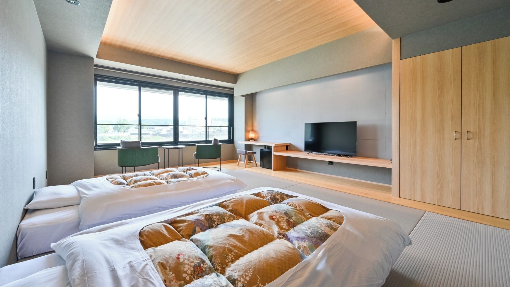 A modern hotel room with two beds, a TV, a desk, and a large window.