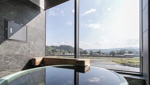 A modern bathroom with a glass-enclosed hot tub, a wooden bench, and a view of a landscape through large windows. - Hitoyoshi Onsen Nabeya (Hitoyoshi)