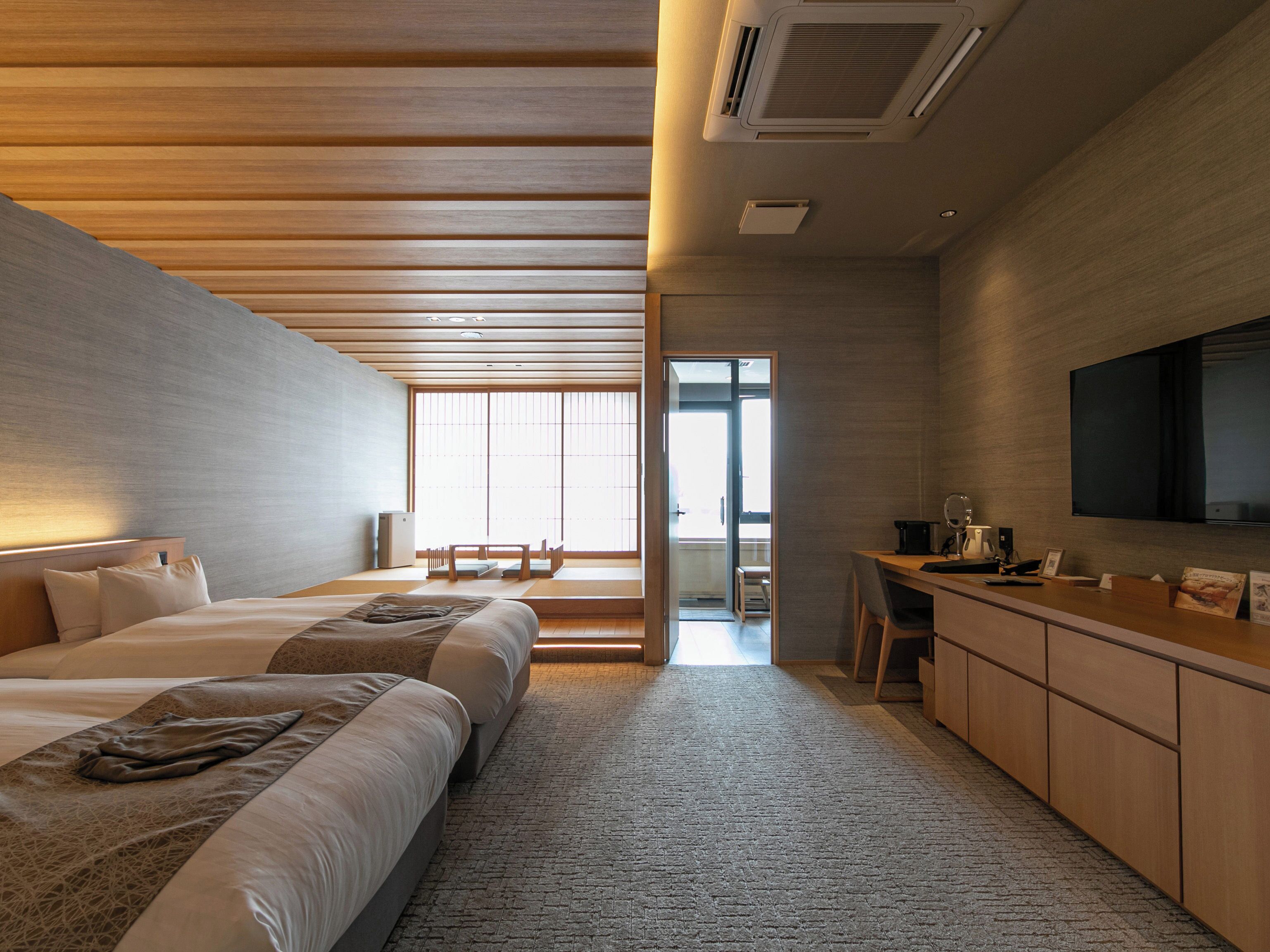 Une chambre d’hôtel moderne, dotée d’un grand lit, d’un bureau et d’une télévision.